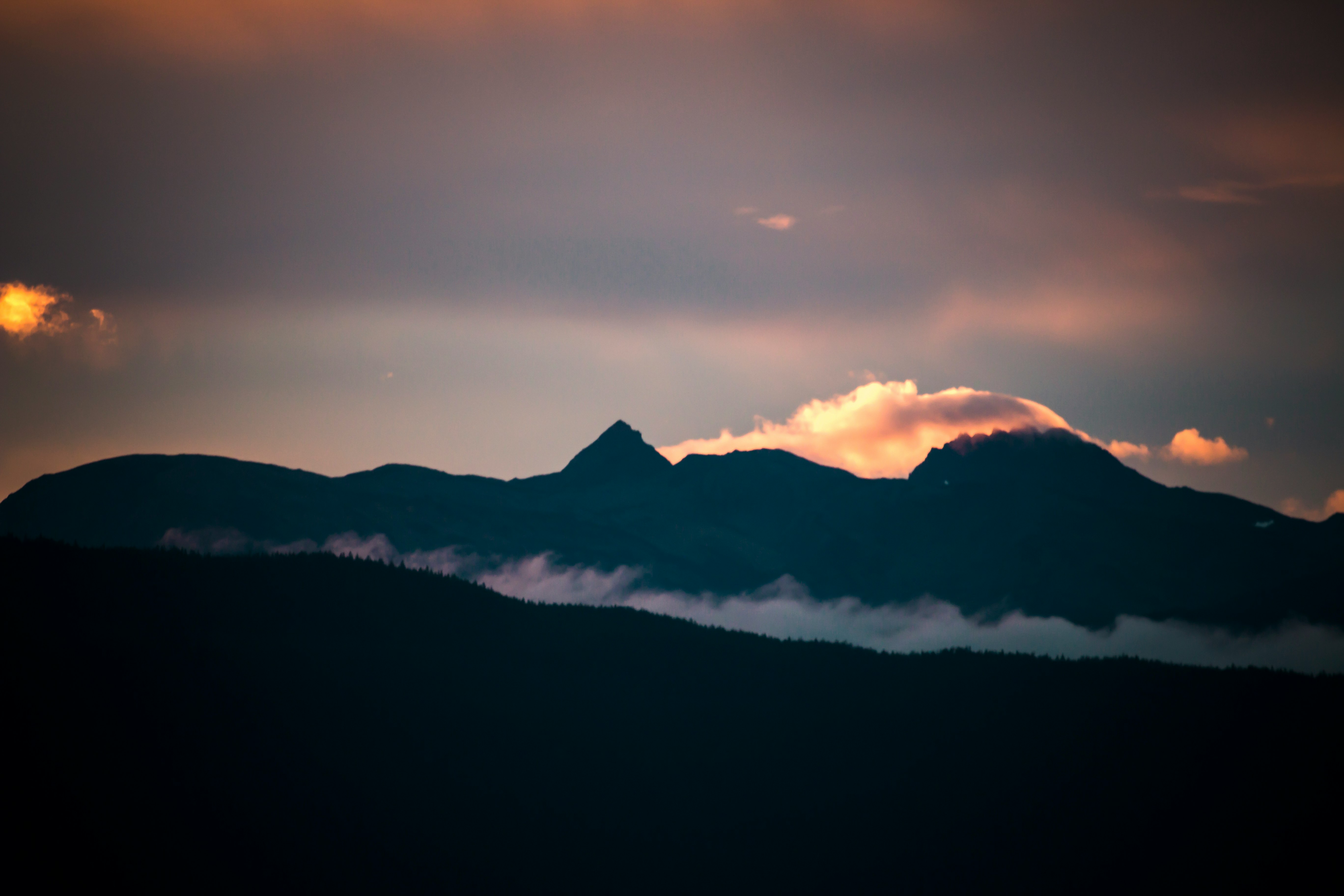 silhouette of mountain with clouds at golden hour